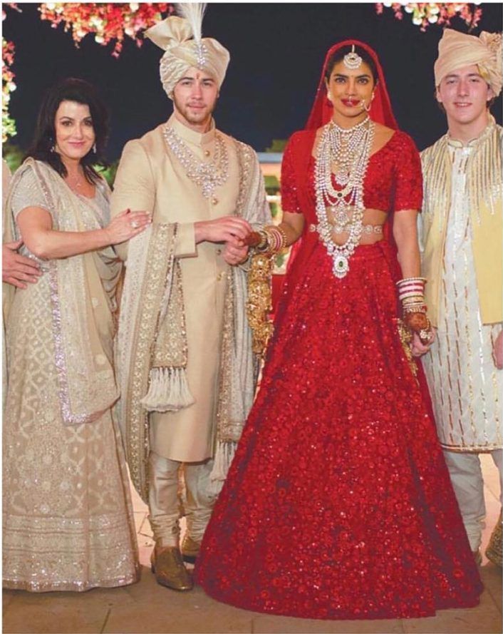 a group of people standing next to each other in formal wear and jewelry on their wedding day