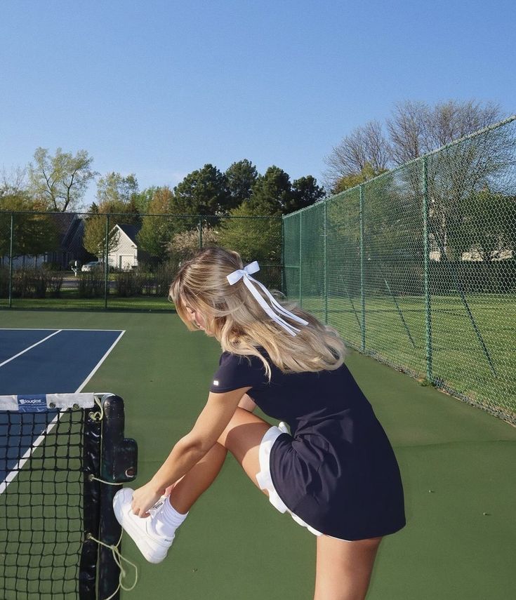 a young woman holding a tennis racquet on top of a tennis ball court