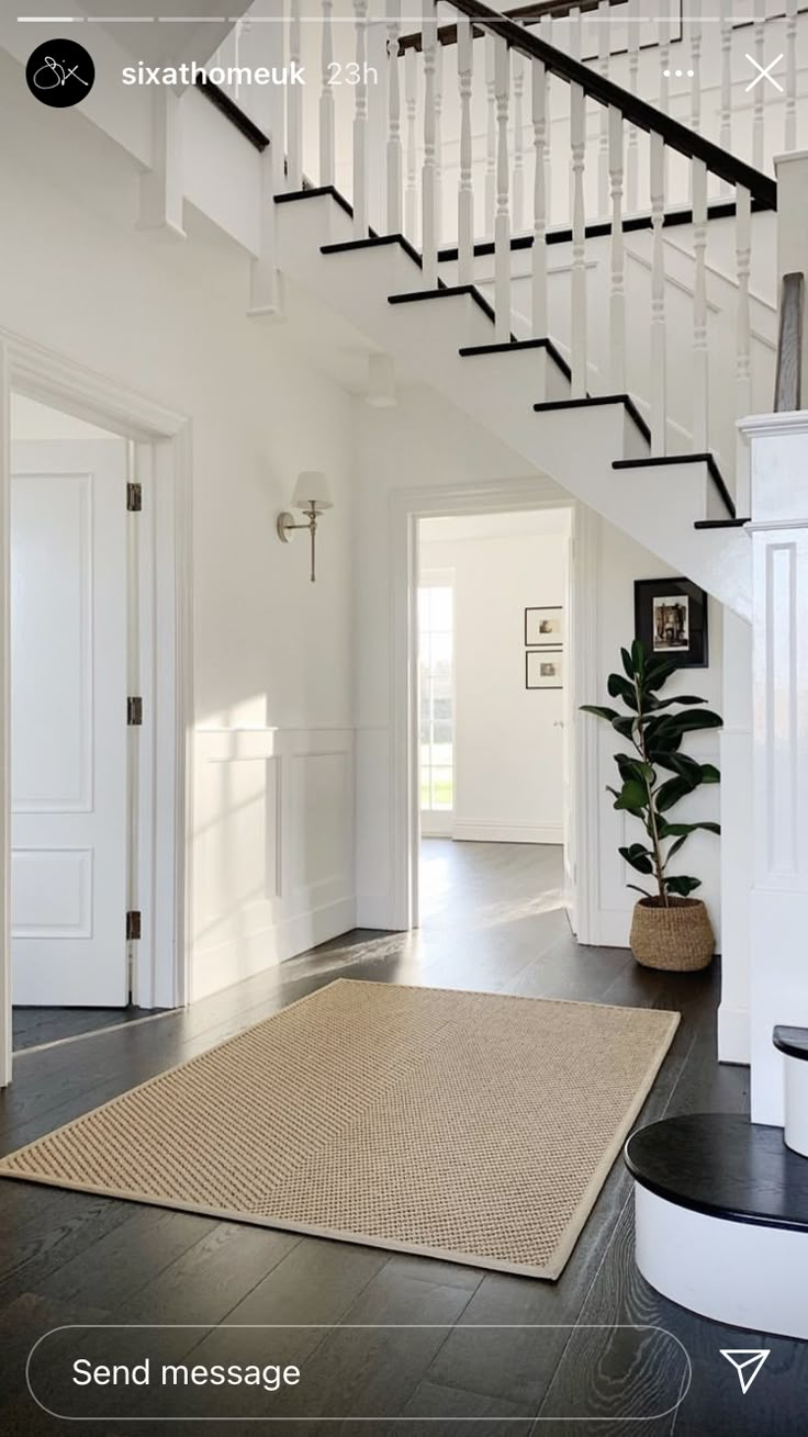 a white staircase with black handrails and a rug on the floor in front of it