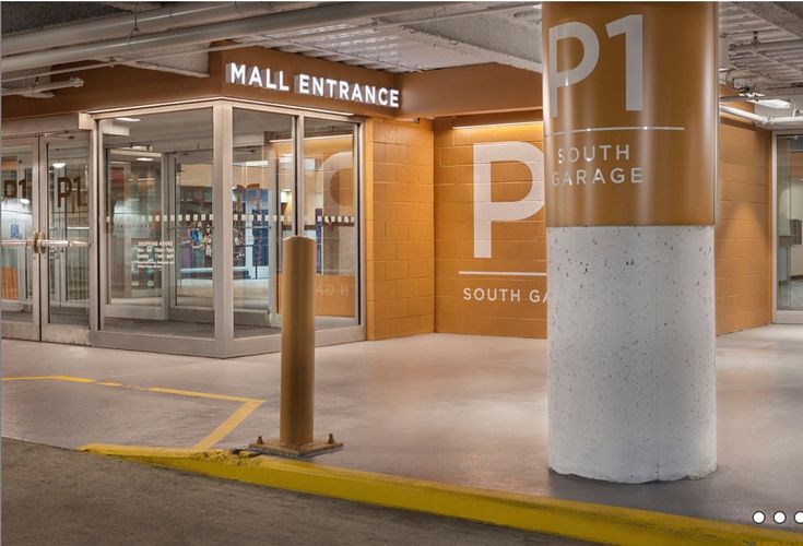 the inside of a mall entrance with glass doors and yellow painted pillars in front of it