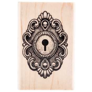 a wooden stamp with an ornate design and a key on the front, in black ink