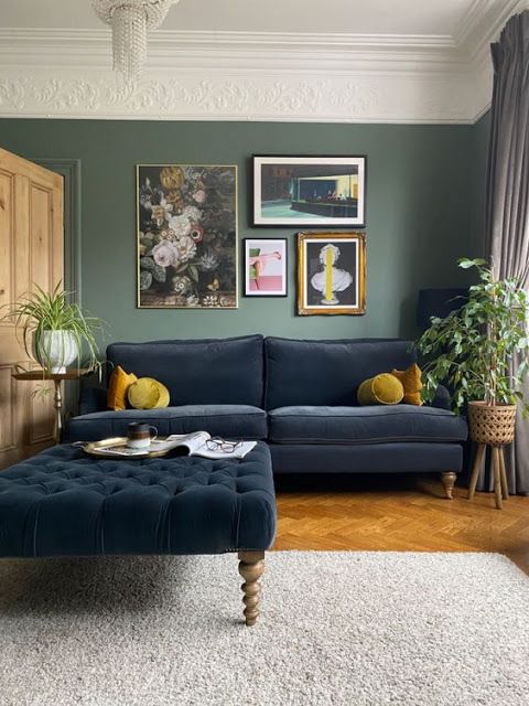 a living room with blue couches and pictures on the wall above them, along with potted plants