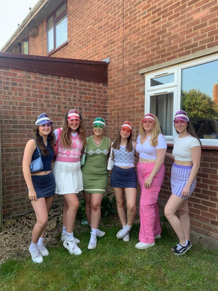 four girls are standing in front of a brick building