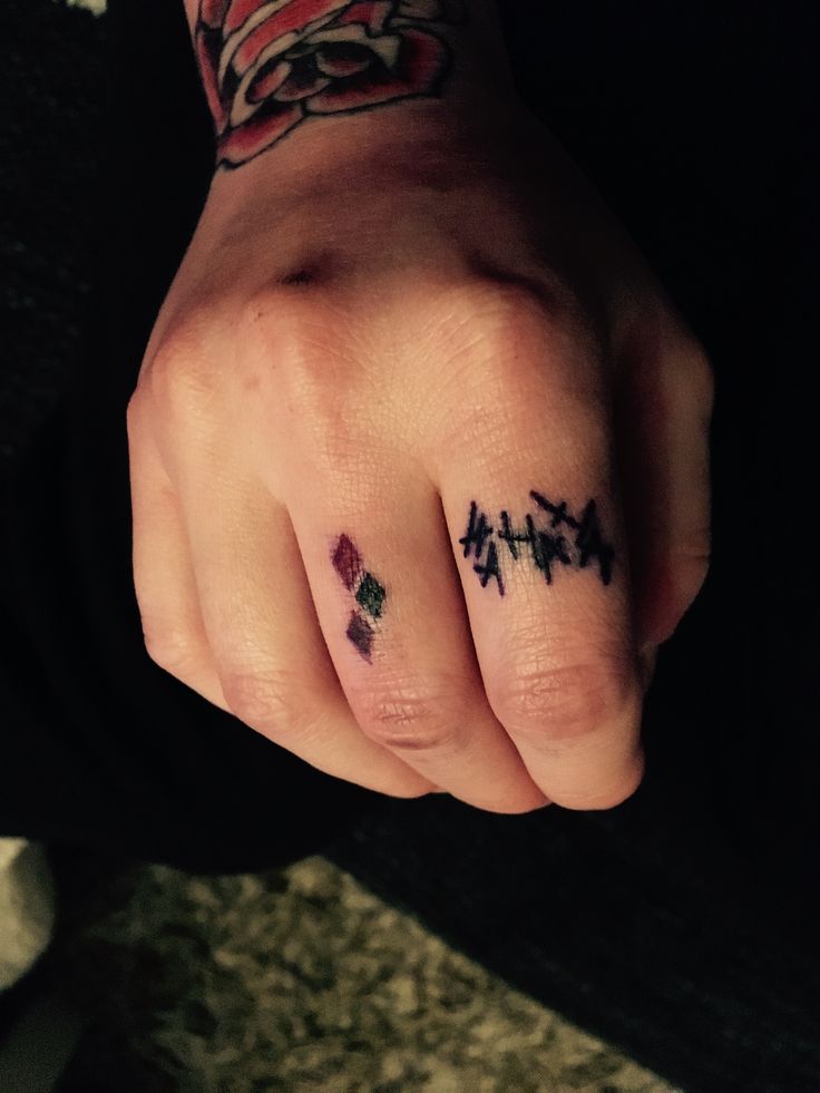 a person's hand with two small tattoos on their fingers and one is holding the other