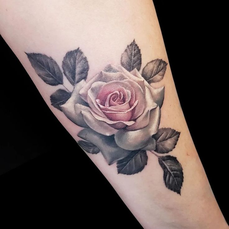 a rose tattoo on the arm with leaves