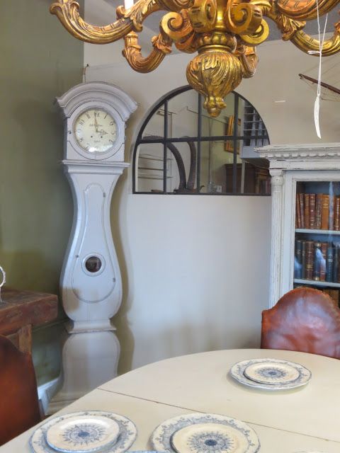 a dining room table with plates on it in front of a bookcase and clock