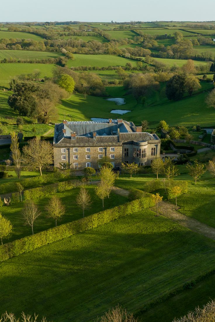 an aerial view of a large building in the middle of a green field