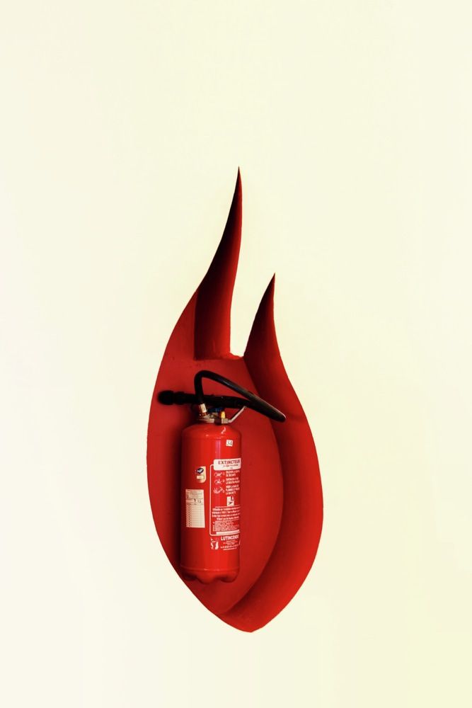 a red fire extinguisher hanging from the side of a wall with scissors