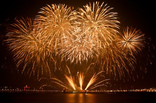 fireworks are lit up in the night sky over water