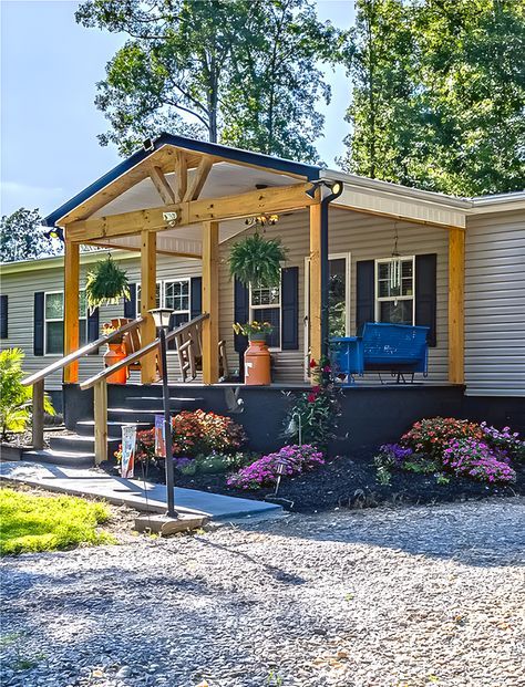 a mobile home sits in the middle of a gravel lot with flowers and trees around it