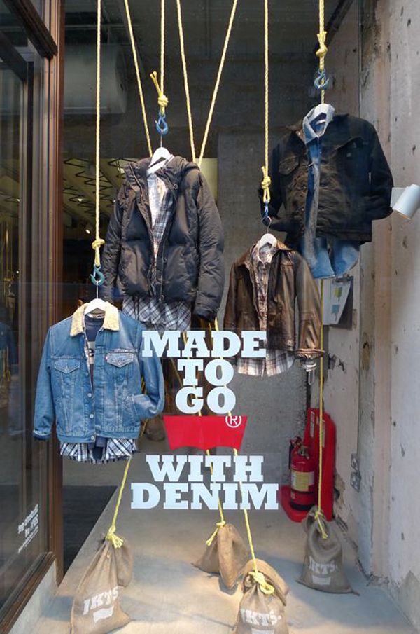 an image of clothes hanging from hooks in the store window with text that reads made to go with denim