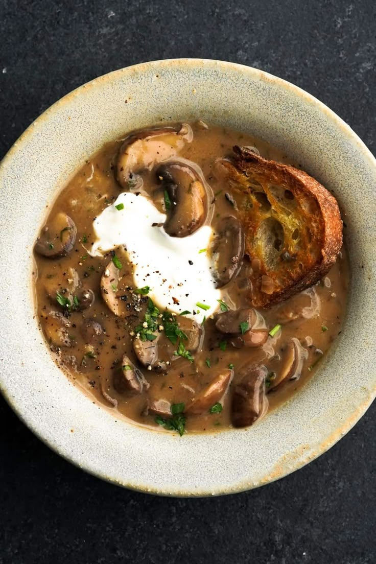 a bowl of mushroom soup with bread and sour cream