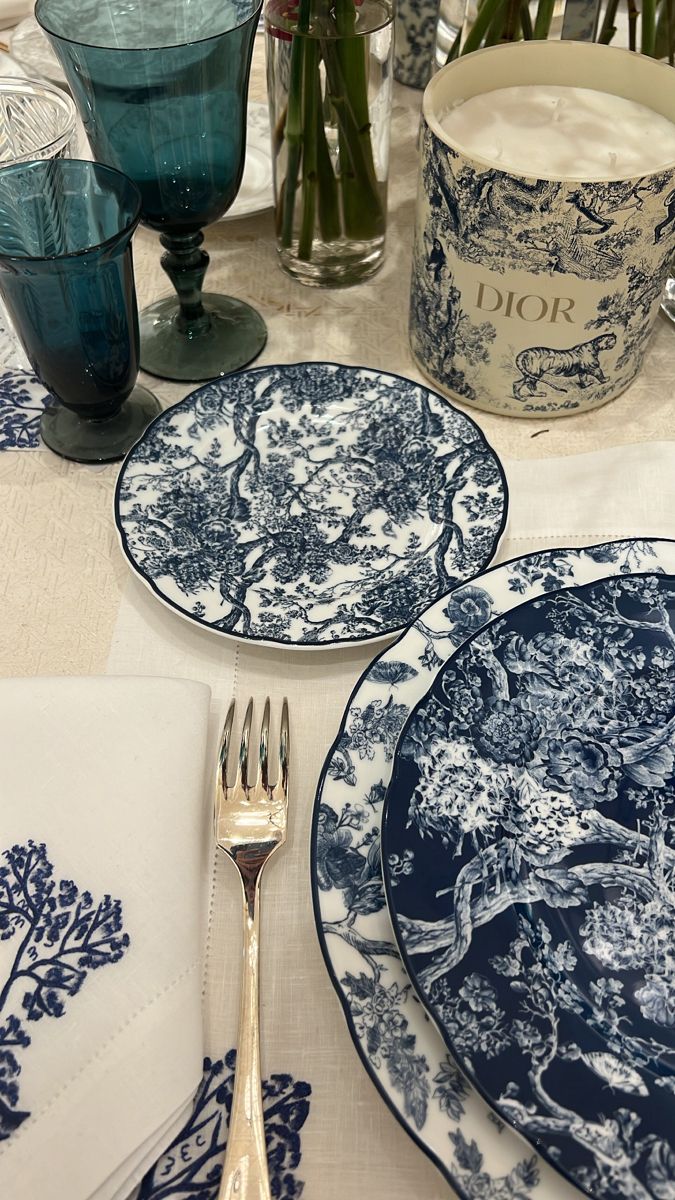 the table is set with blue and white plates, silverware, and napkins