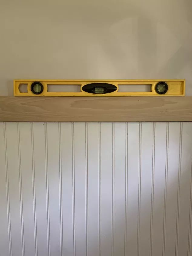 a yellow radio sitting on top of a wooden shelf next to a white painted wall