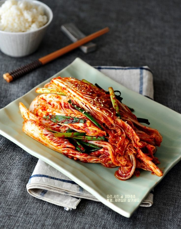 a plate with some food on it next to a bowl of rice and chopsticks