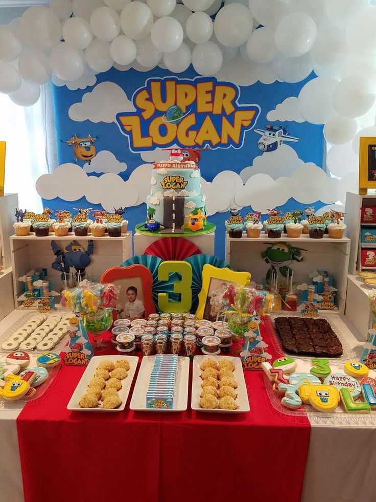 a table topped with lots of desserts and balloons in the shape of clouds on top of it