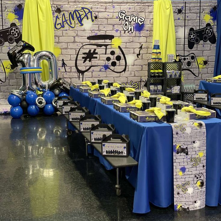 a table set up for a party with blue and yellow decorations on the wall behind it