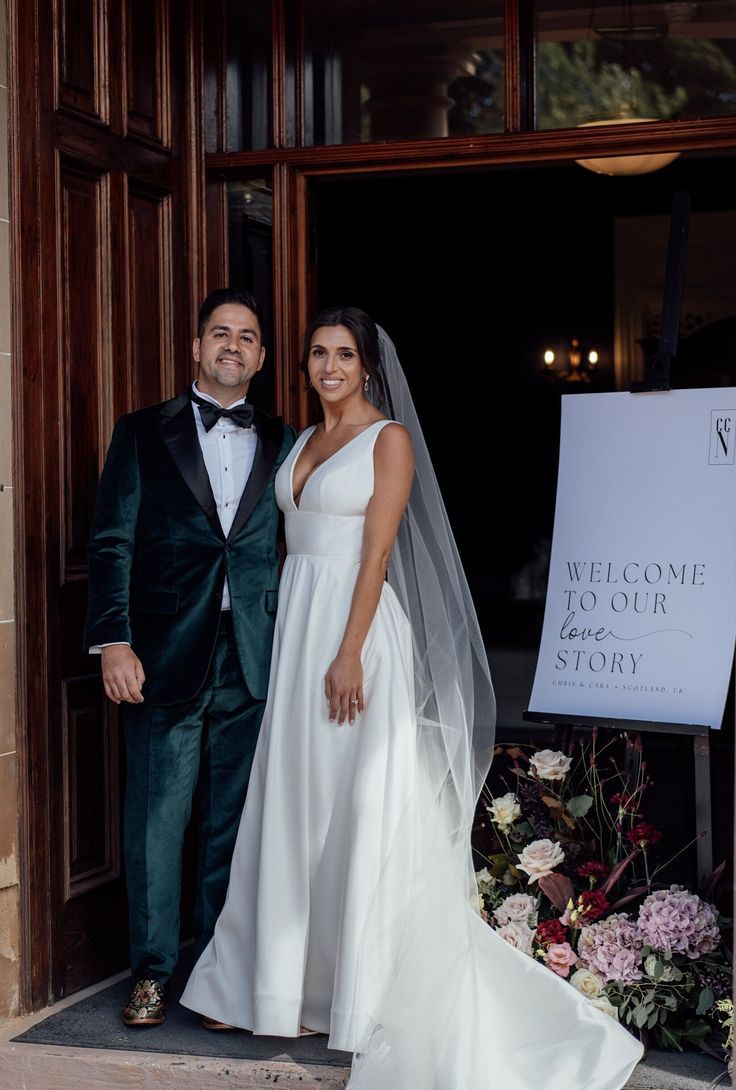 a bride and groom standing in front of a welcome to our story sign at their wedding