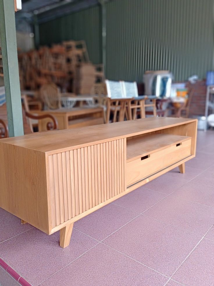 a large wooden entertainment center sitting on top of a pink tile floor next to tables and chairs