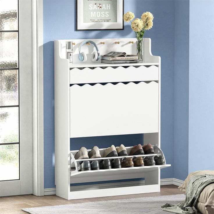 a white shoe rack with shoes on it in a blue room next to a bed