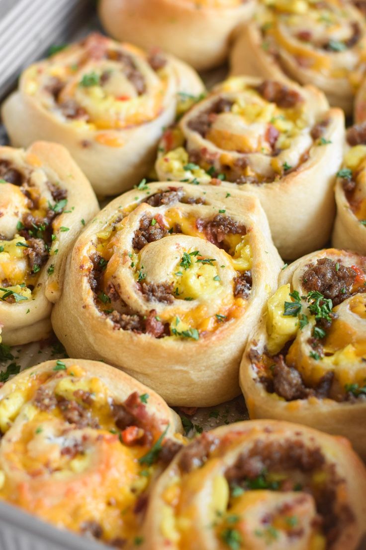 several rolls with meat and cheese in a baking pan on top of a wooden table