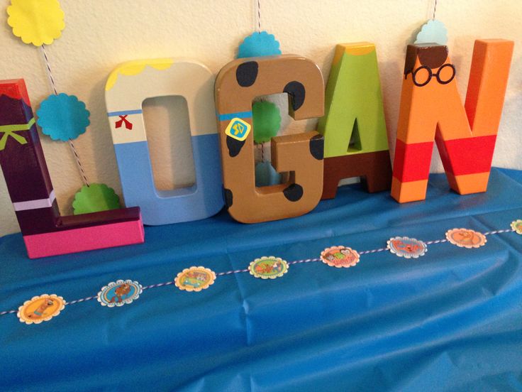 the letters are made out of wood and have decorations around them on a blue table cloth