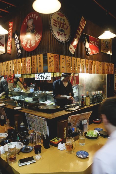 people are sitting at a restaurant counter with food on the table and signs above them