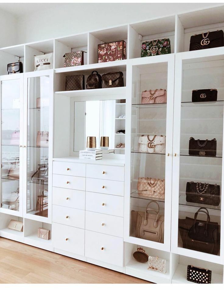 a large white closet with many purses and handbags on it's shelves