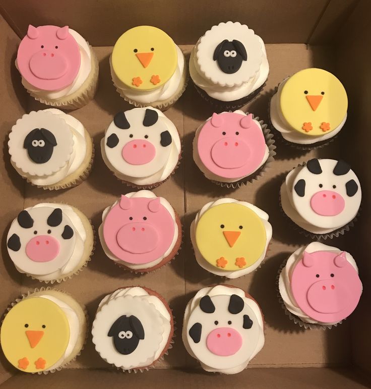 twelve cupcakes decorated with farm animals and birds in a cardboard box on top of a table