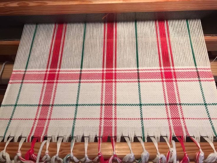 a red and white checkered table cloth hanging on a loom