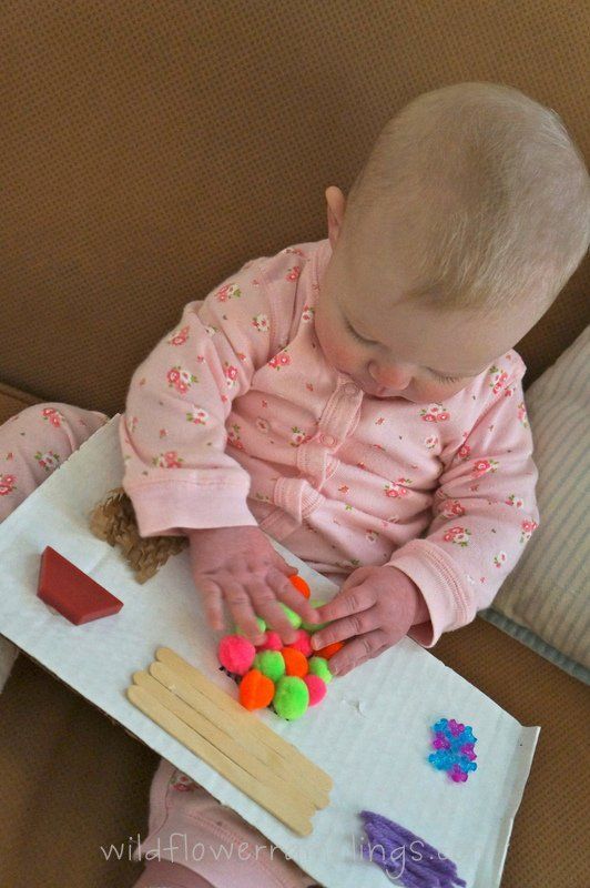 a baby sitting on the couch playing with some colorful beads and paper machs in front of her