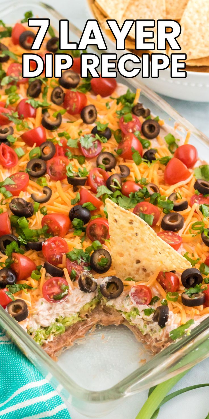 a casserole dish filled with tortilla chips, black olives and tomatoes