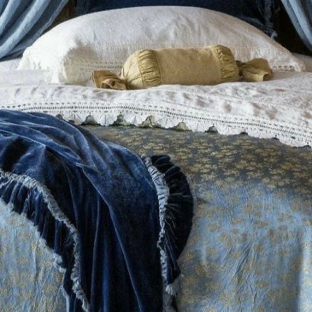 a bed with blue and white bedspread, pillows and blankets on top of it