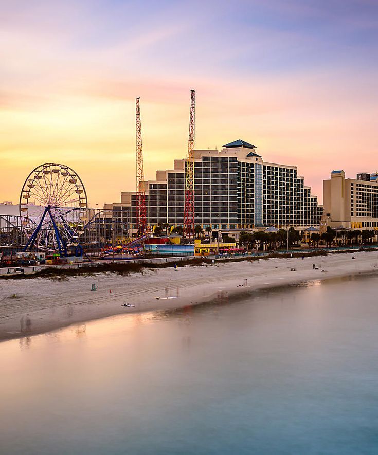 the beach and ferris wheel at sunset in front of hotels