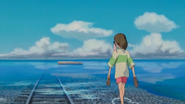 a woman walking along train tracks next to the ocean