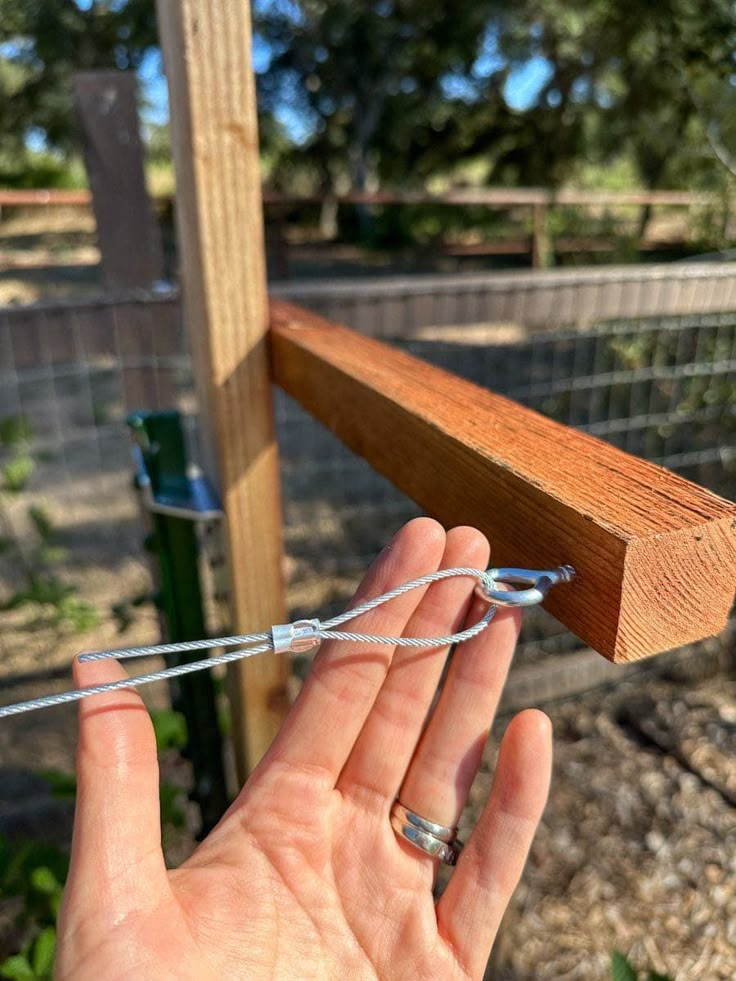 someone is holding their hand up to the top of a fence post with barbed wire