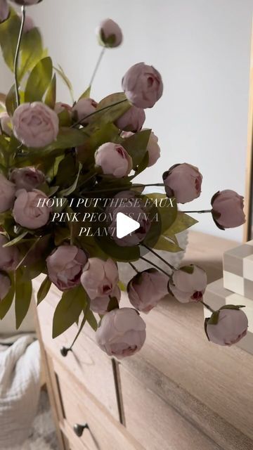 a bouquet of pink flowers sitting on top of a wooden dresser next to a mirror