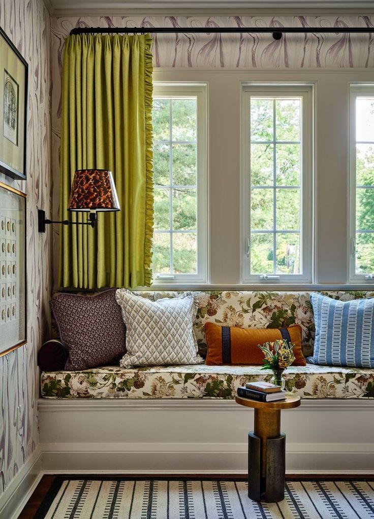 a living room filled with lots of furniture next to two windows covered in green curtains