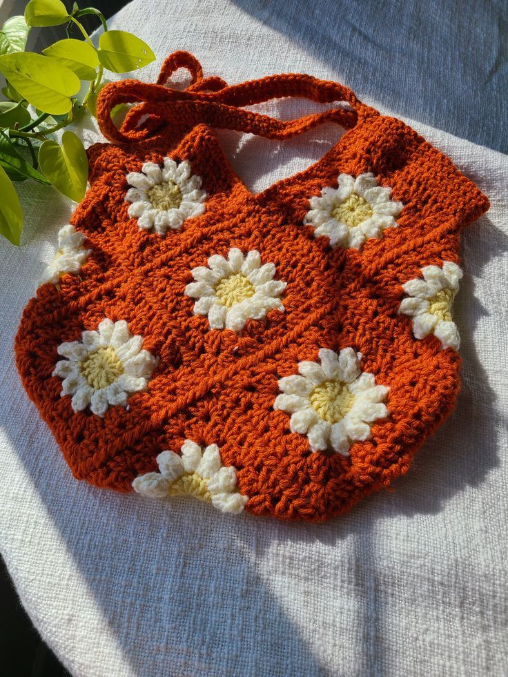 an orange crocheted purse sitting on top of a table next to a plant