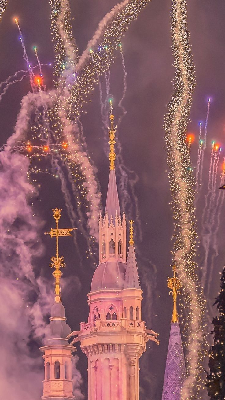 fireworks are lit up in the night sky above a church steeple and spires