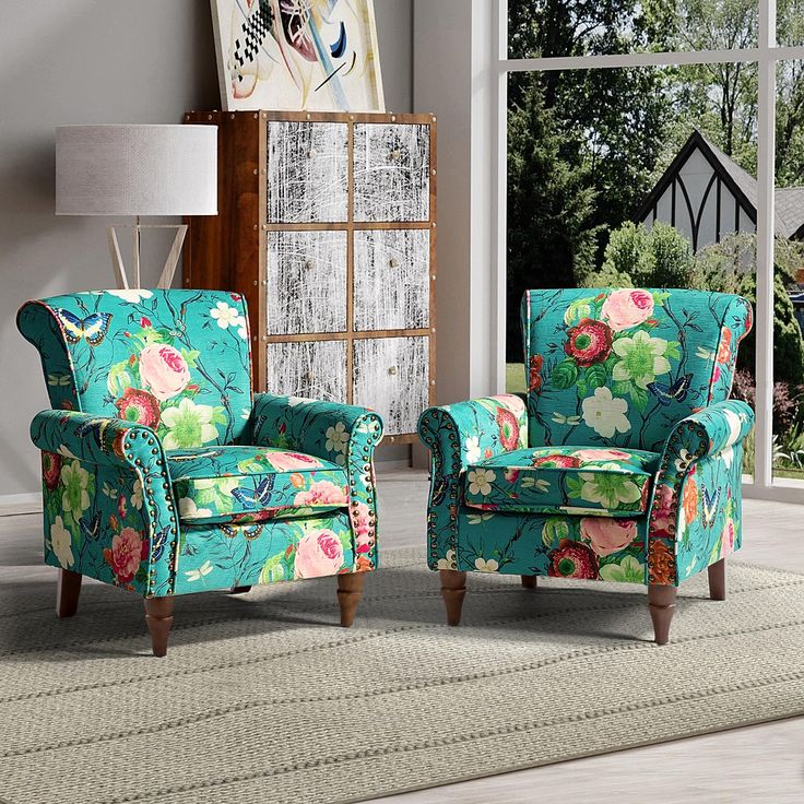 a living room with two chairs and a rug in front of a window that has a painting on the wall