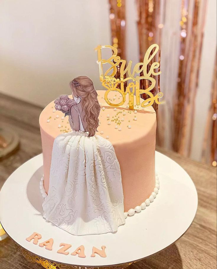 a pink and gold wedding cake with a bride on top