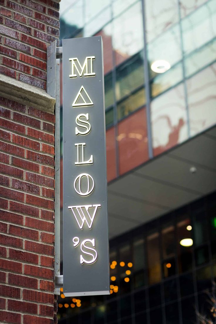 a neon sign that reads maslow's hanging from the side of a building