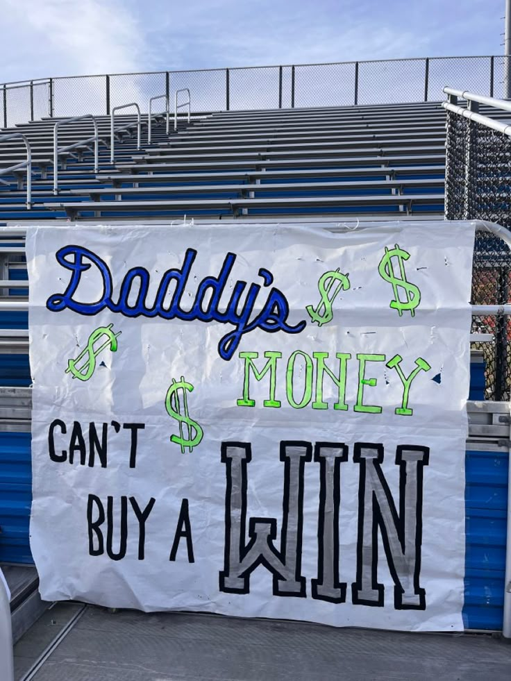 a sign that says daddy's money can't buy a win in front of a bleachers