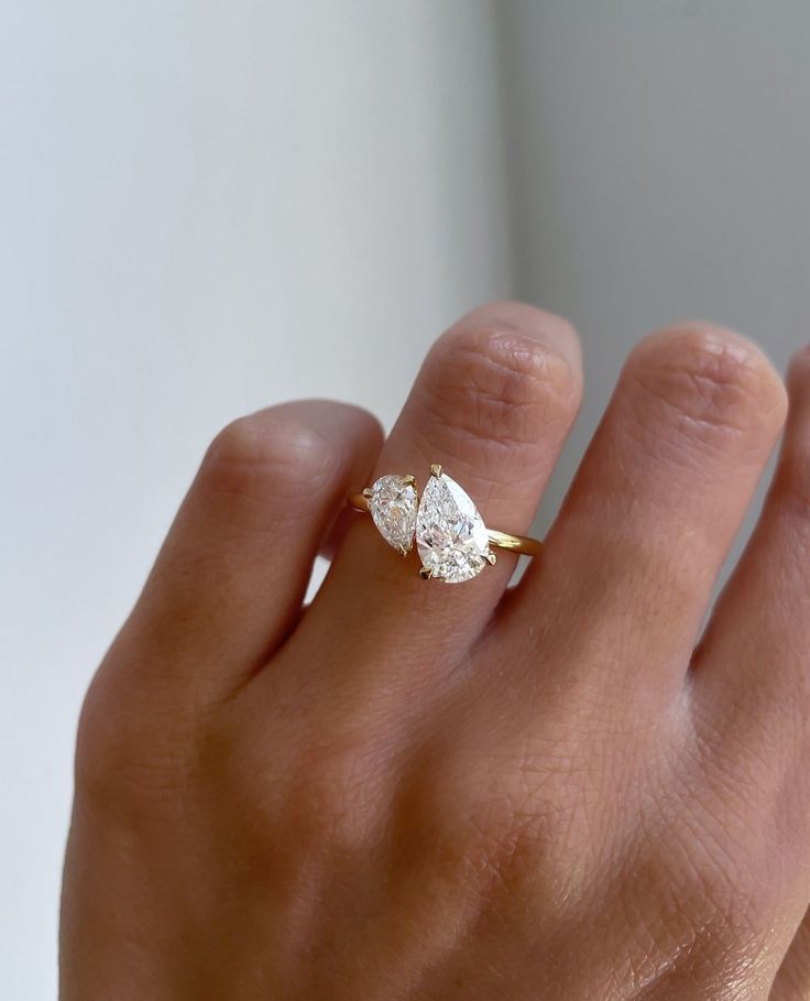 a woman's hand with a diamond ring on top of her finger, showing the side view