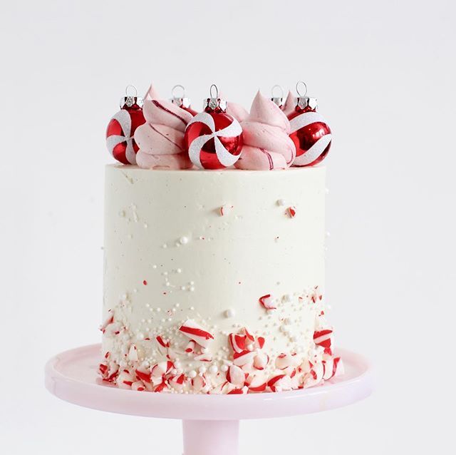 a white cake topped with candy canes on top of a pink cake platter