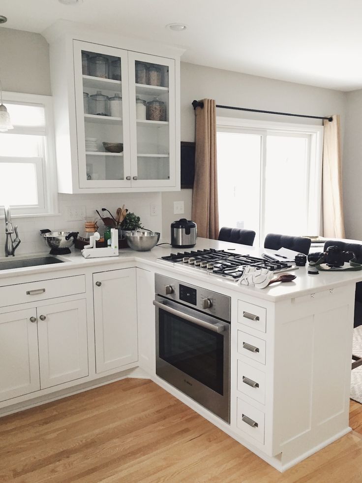 a kitchen with white cabinets and an oven in the center, along with wooden floors