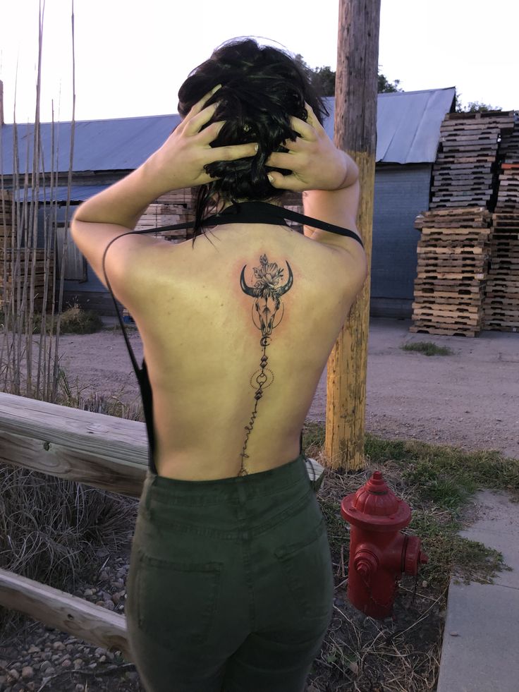 a woman with a tattoo on her back standing next to a fire hydrant