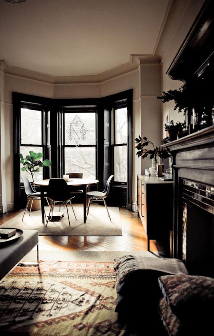 a living room filled with furniture next to two large windows and a fire place in front of a fireplace