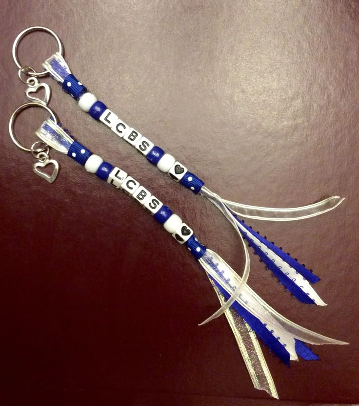 two blue and white scissors are on a brown surface with metal hooks attached to them